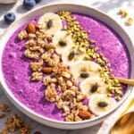 A vibrant blueberry smoothie bowl with Greek yogurt served in a ceramic bowl on marble.