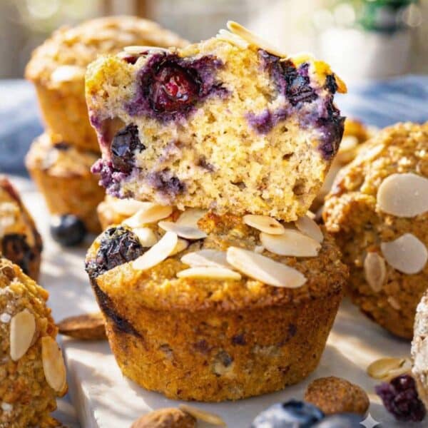 Almond flour blueberry muffins with Greek yogurt stacked neatly under bright, natural light.