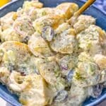 Bowl of Greek yogurt potato salad on marble table by bright window light.