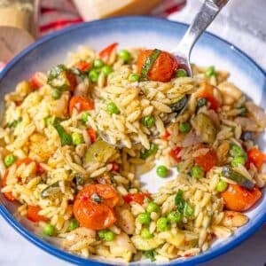 Bowl of orzo primavera with basil and black pepper.