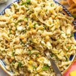 Bright bowl of lemon pasta salad with feta and herbs near window light.