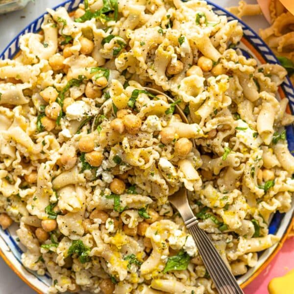 Bright bowl of lemon pasta salad with feta and herbs near window light.