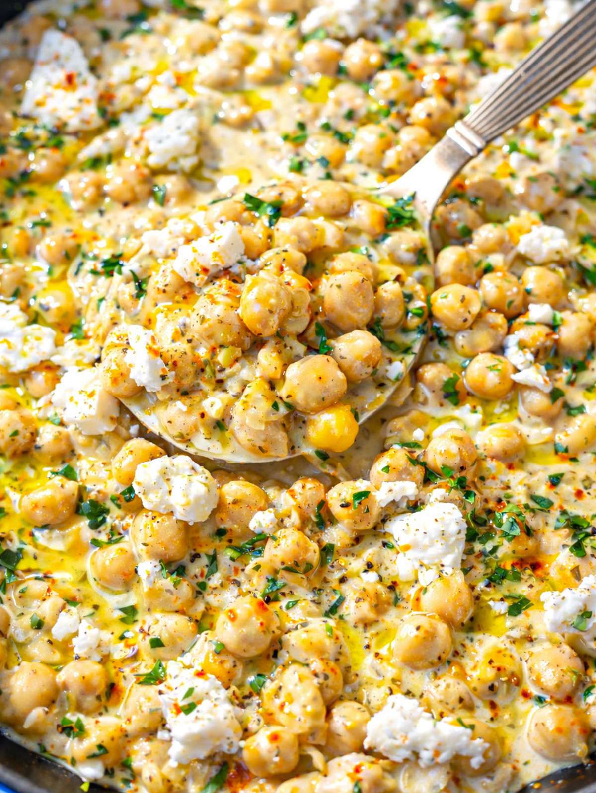 Close-up of creamy chickpea lemon skillet with yogurt sauce coating chickpeas.