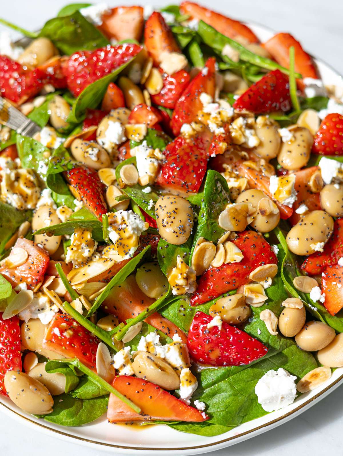 Close up of strawberry spinach salad with juicy strawberries creamy feta and toasted almonds.
