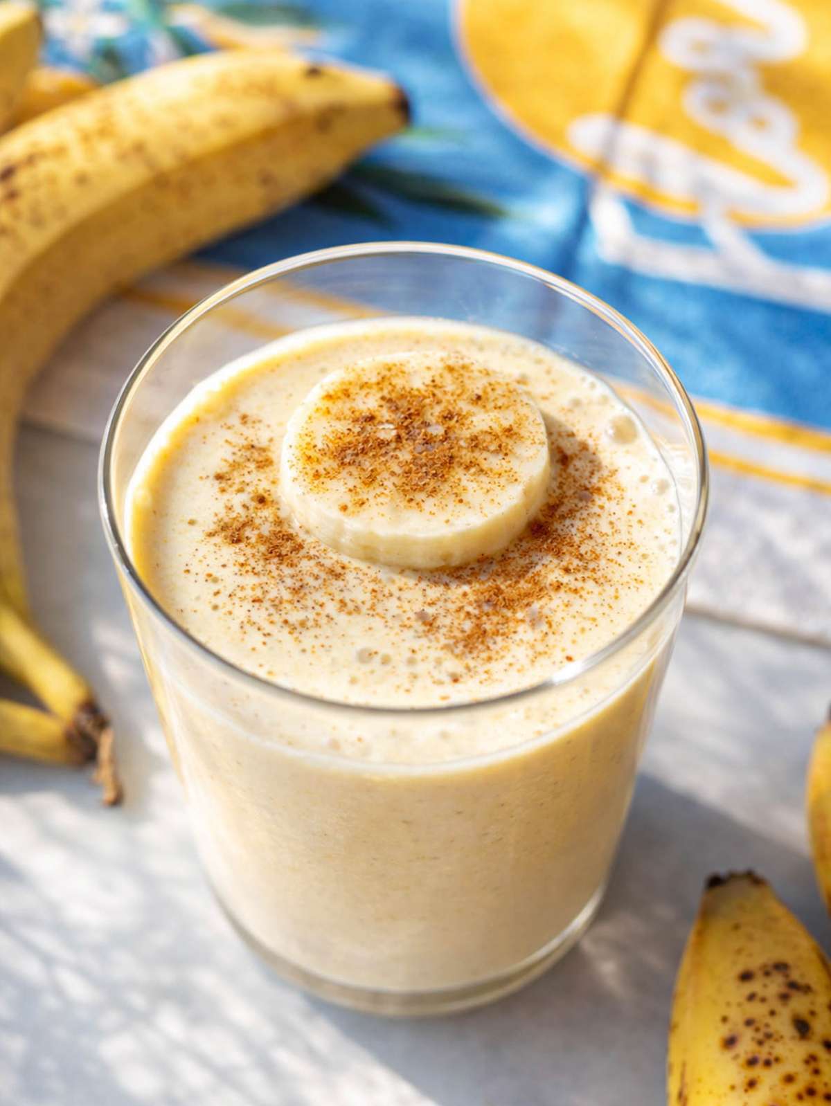 Close up of thick banana smoothie showing creamy texture inside clear glass.