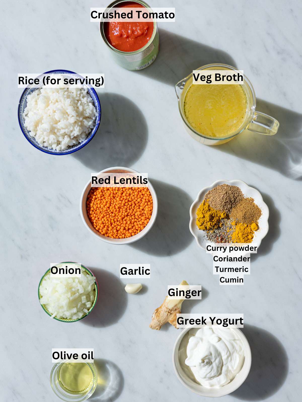 Dried red lentils and vibrant spices in small bowls on a bright white marble surface.