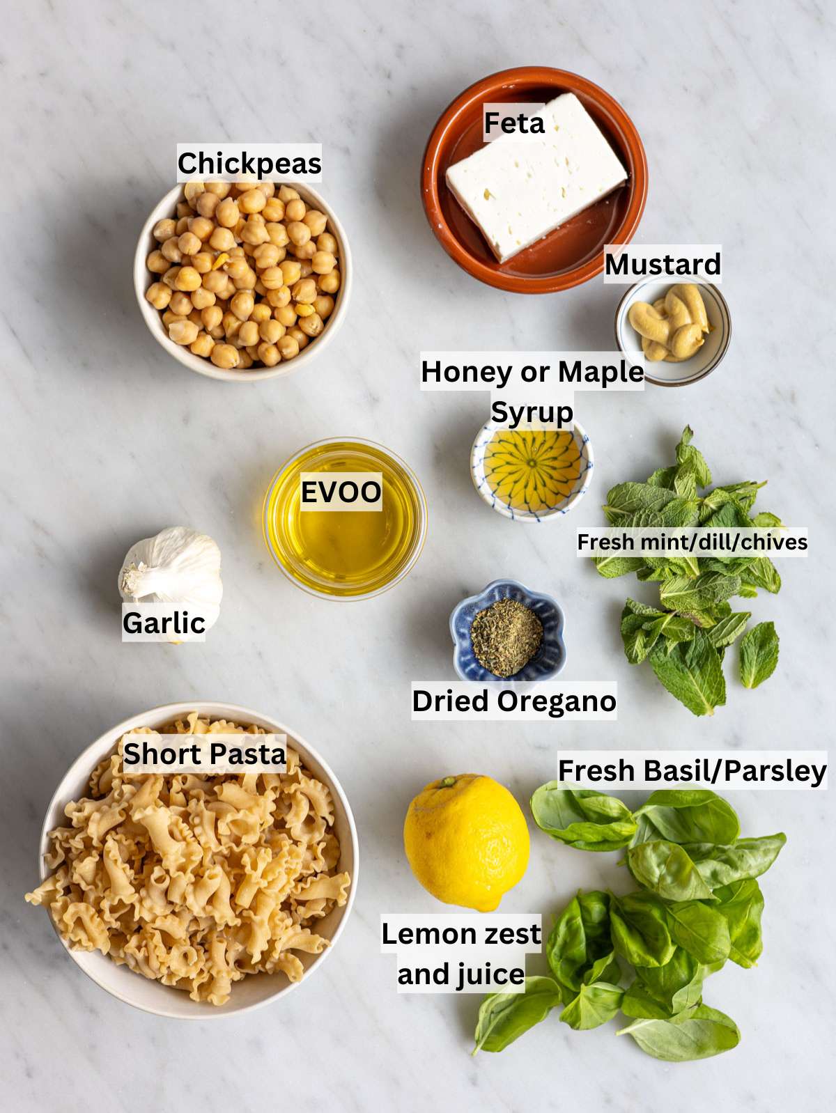 Fresh ingredients for lemon pasta salad on marble surface near window with natural light.
