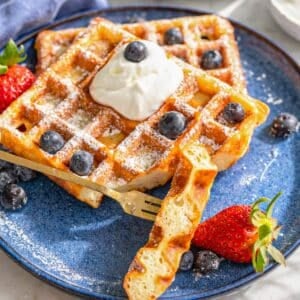 Freshly cooked Greek yogurt waffles on plate with yogurt and honey near window with soft light.