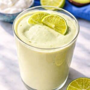 Glass of Greek yogurt avocado smoothie on marble table with soft natural light.