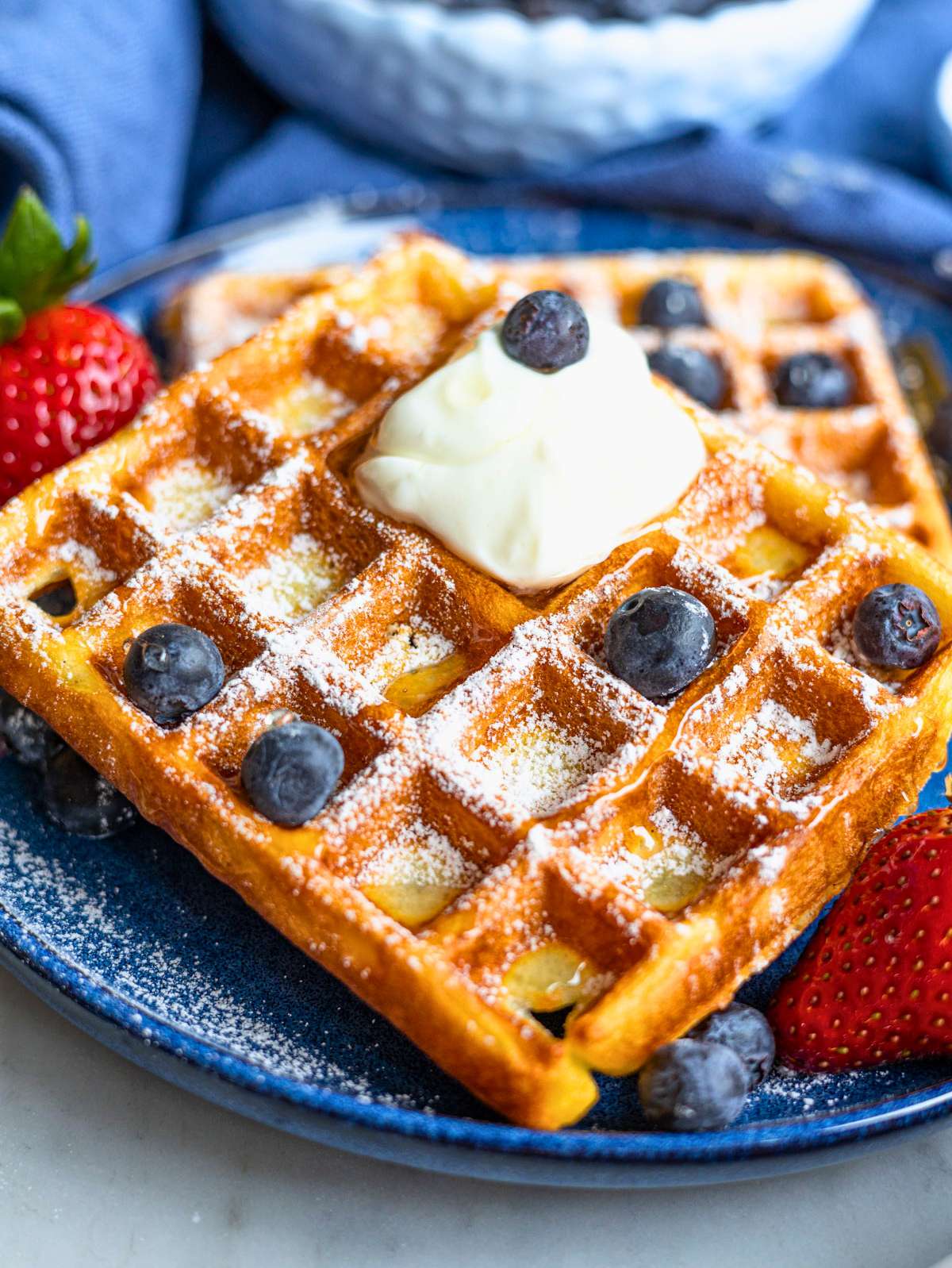 Golden Greek yogurt waffles with yogurt and honey on marble table.