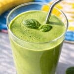Greek Yogurt Green Smoothie in tall glass with spinach leaf garnish.