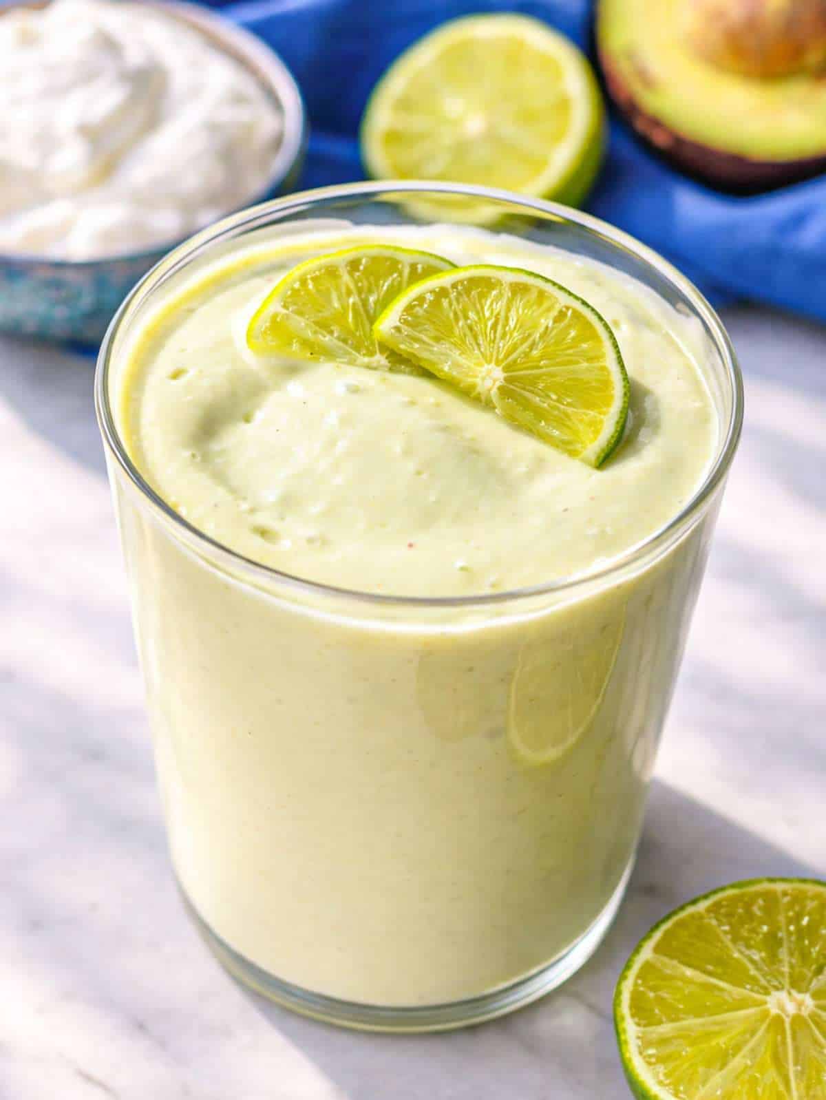 Greek yogurt avocado smoothie in glass with creamy texture near window light.