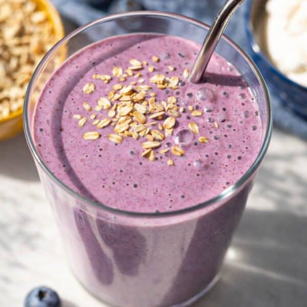 Greek yogurt breakfast smoothie in tall glass with blueberries on marble surface in soft natural light.