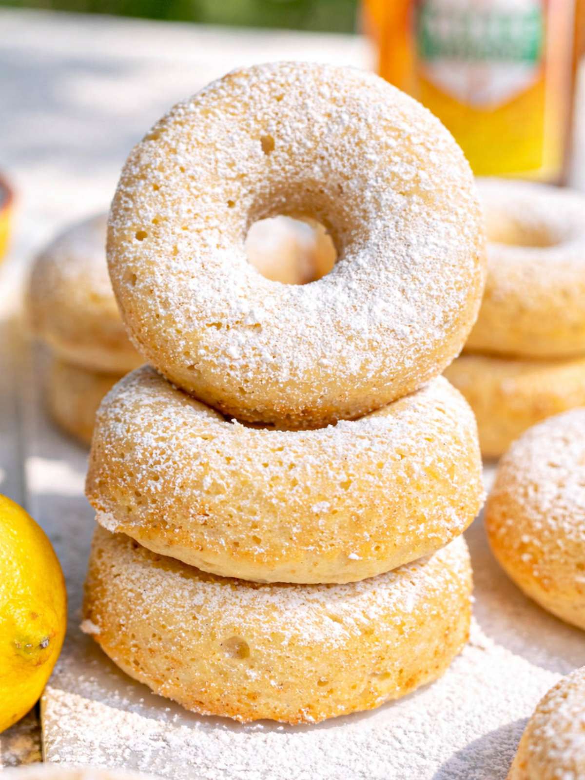 Greek yogurt cake donuts dusted with powdered sugar on marble table near window.