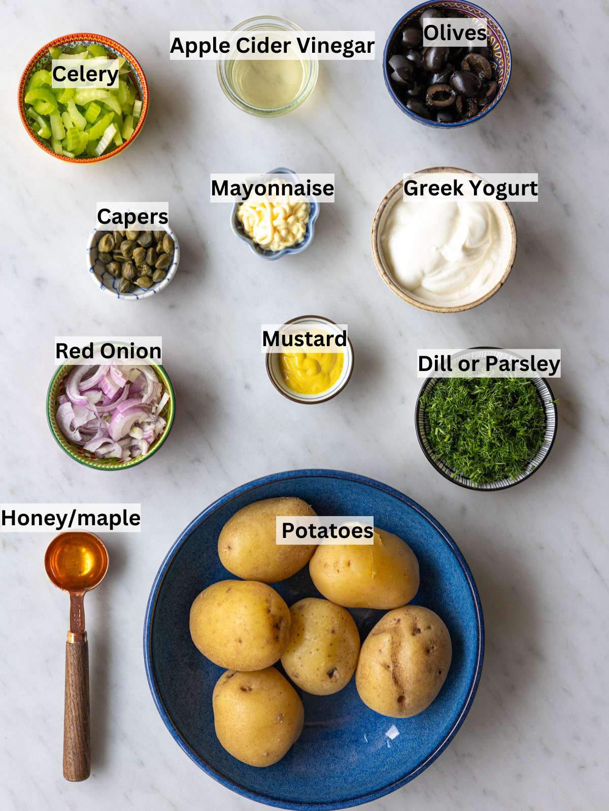Ingredients for Greek yogurt potato salad arranged on marble table in natural light.
