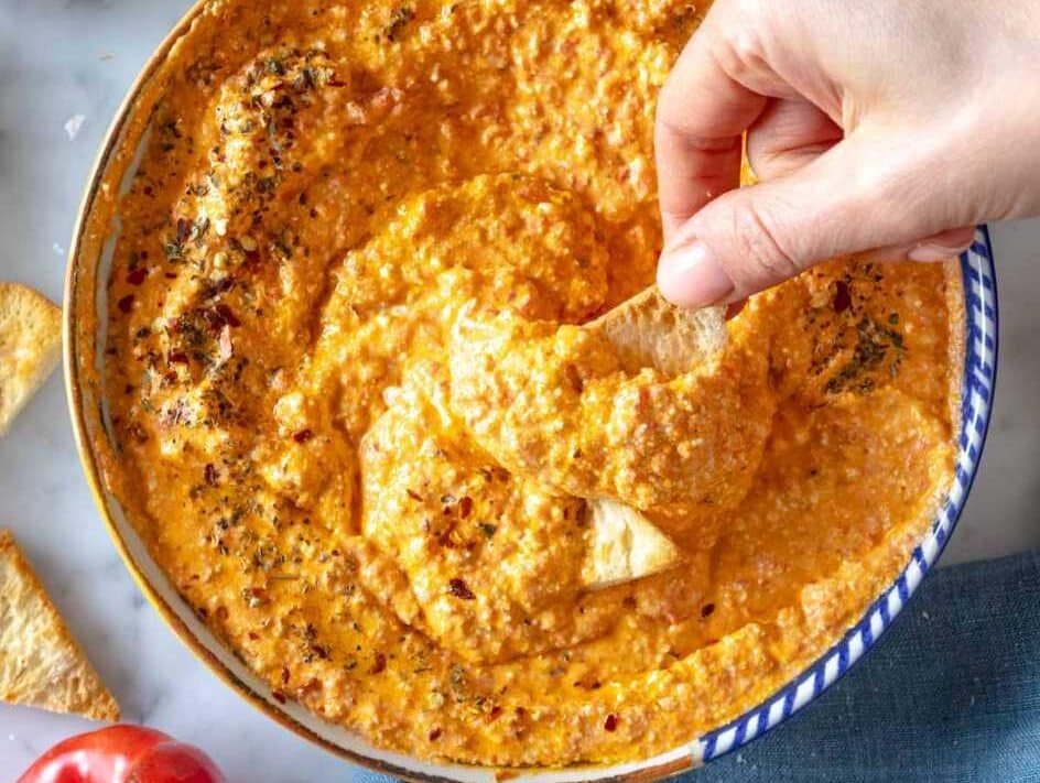 Louise dipping pita chips in Tirokafteri.