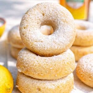 Plate of Greek yogurt cake donuts with lemon zest and powdered sugar in bright natural light.