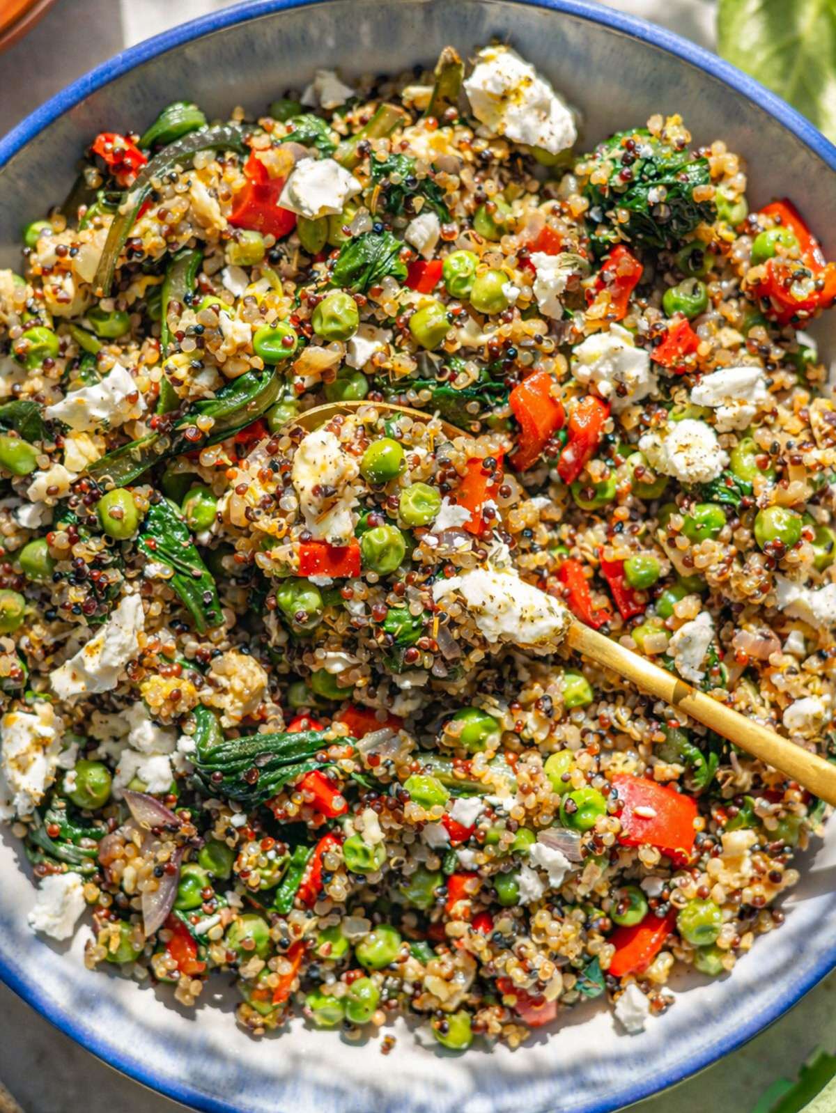 Savory quinoa breakfast bowl with eggs spinach and feta served in bowl on marble surface.