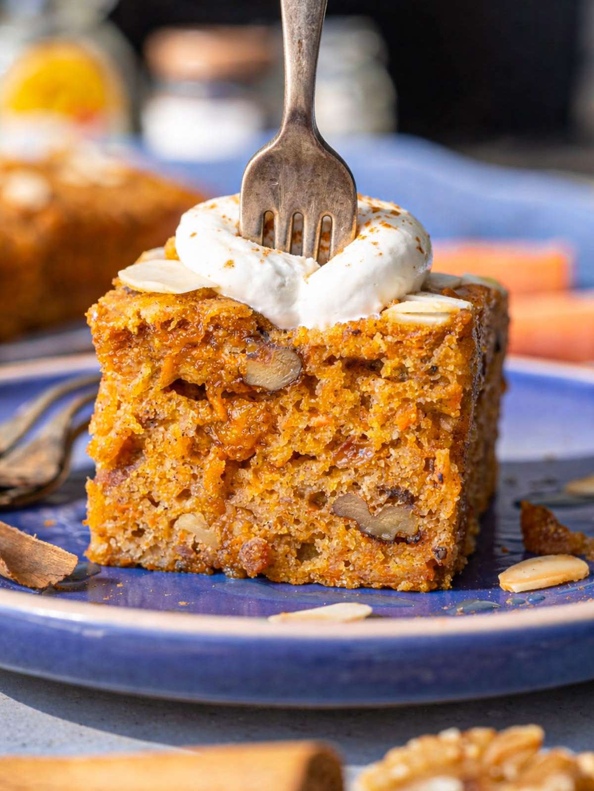 Sliced carrot cake with yogurt drizzle on marble table by window.