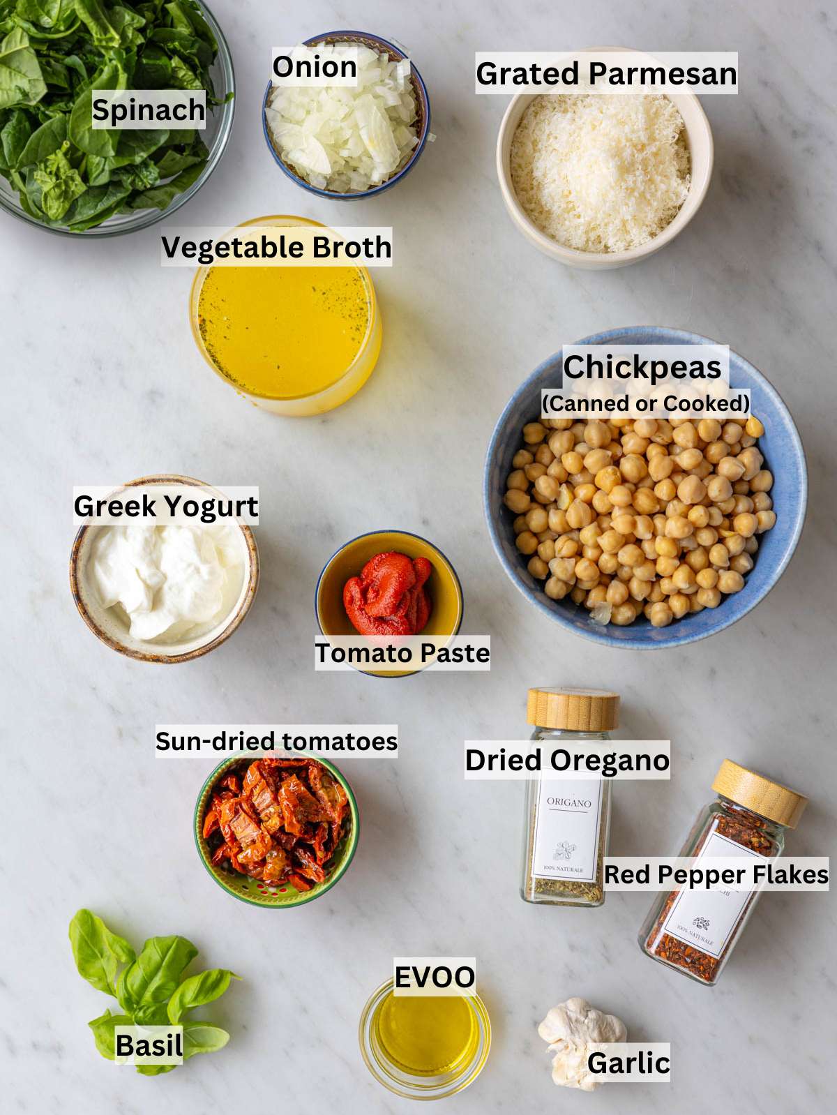 Spinach, chickpeas, and other ingredients arranged on a bright marble surface in natural light.