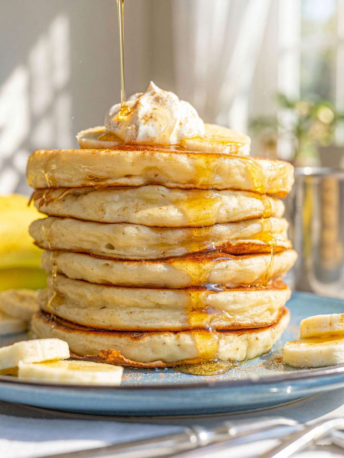 Stack of Greek yogurt banana pancakes with sliced banana and drizzle of syrup.