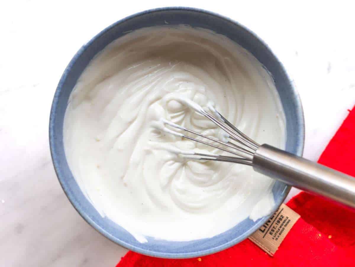 Step 1 Mixing Greek yogurt with lemon zest and honey in bowl on marble surface.