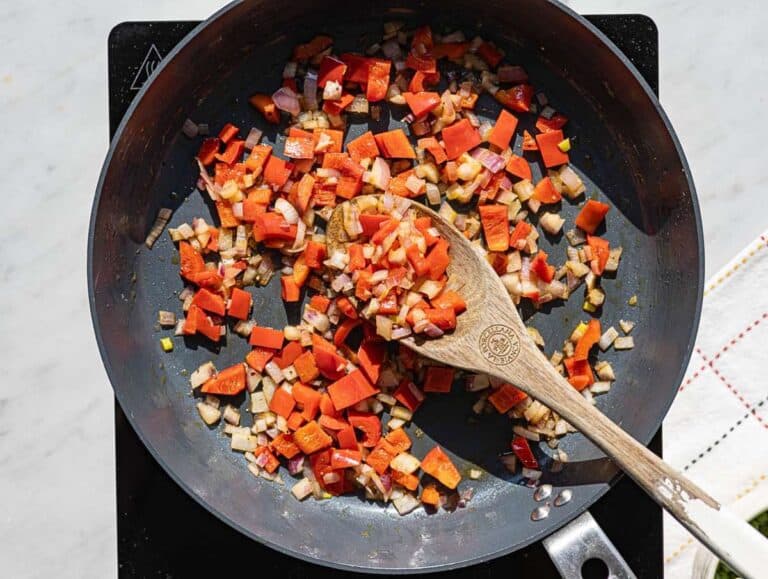Step 1 Sliced red onion and bell pepper cooking in skillet with olive oil.
