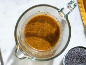 Step 1 Whisking balsamic poppy seed dressing in small bowl on marble surface near window.