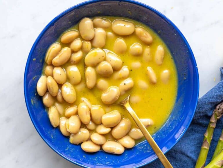 Step 1 Whisking lemon dressing in a bowl with large white butter beans marinating inside.