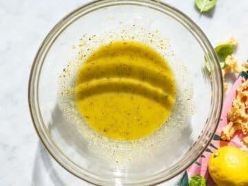Step 1 Whisking lemon dressing in bowl on marble counter with natural daylight.
