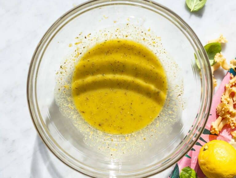 Step 1 Whisking lemon dressing in bowl on marble counter with natural daylight.