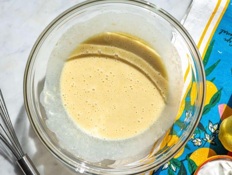 Step 1 Whisking yogurt egg and sugar mixture in glass bowl on marble surface.