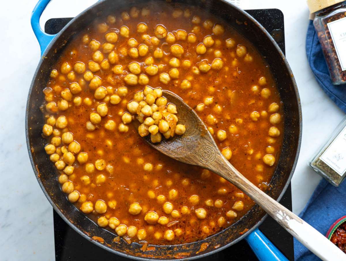 Step 2 Chickpeas and savory broth simmering gently in a wide pan under bright natural light.