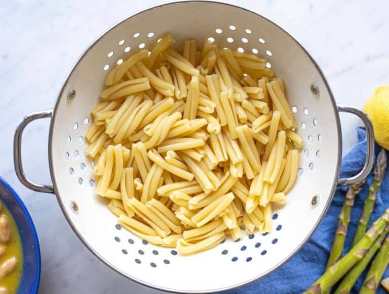 Step 2 Drained short pasta in a white colander catching the bright morning window light.