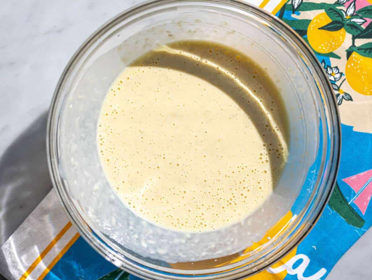 Step 2 Mashed banana mixed with yogurt, egg, and milk in a glass bowl.