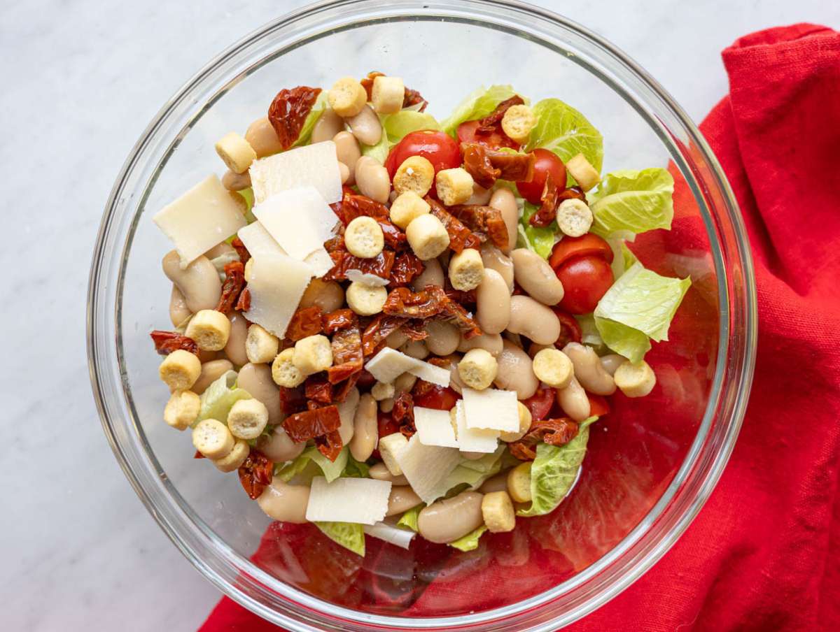 Step 2 Mixing butter beans romaine tomatoes sun dried tomatoes Parmesan and croutons in large bowl.
