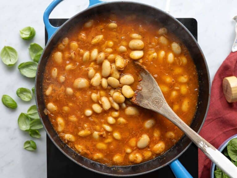 Step 2 Plump butter beans being tossed in a rich tomato and garlic base in a pan.