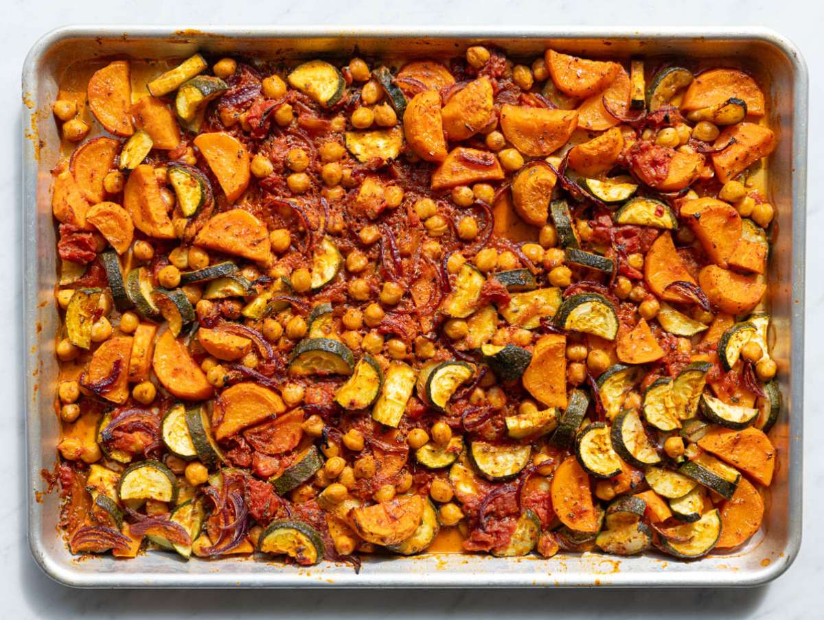 Step 2 Roasted vegetables caramelizing on baking tray with tomatoes and herbs.