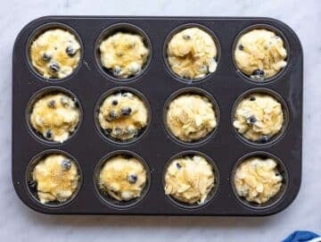 Step 3 Muffin batter scooped into pan with brown sugar topping in bright natural light.