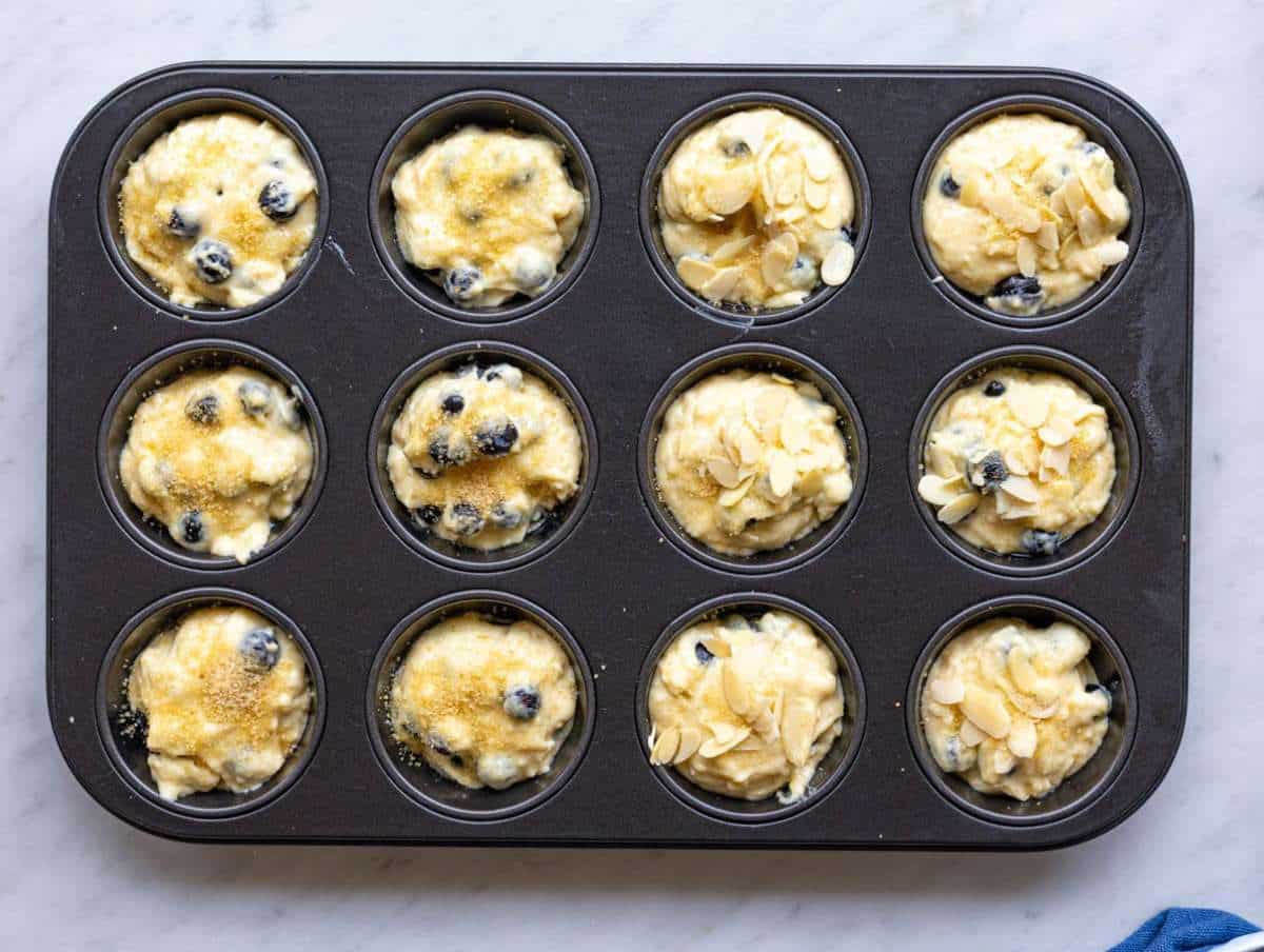 Step 3 Muffin batter scooped into pan with brown sugar topping in bright natural light.