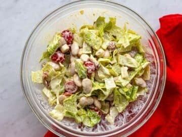 Step 3 Tossing butter bean Caesar salad with creamy dressing until evenly coated.