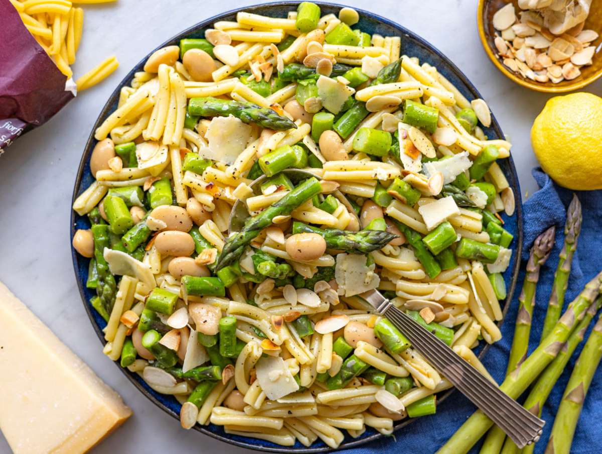 Step 4 Garnishing the finished lemon asparagus pasta salad with toasted almonds and shaved cheese.