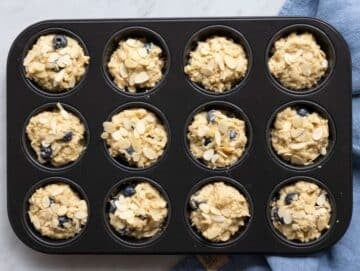 Step 4 Muffin batter with blueberries scooped into a muffin tin.