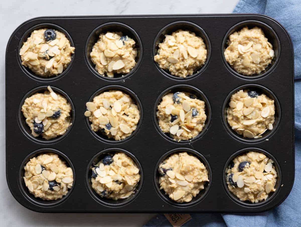 Step 4 Muffin batter with blueberries scooped into a muffin tin.