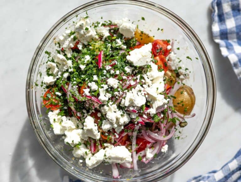 Step 4 Potatoes mixed with tomatoes olives capers herbs and feta in a large bowl.