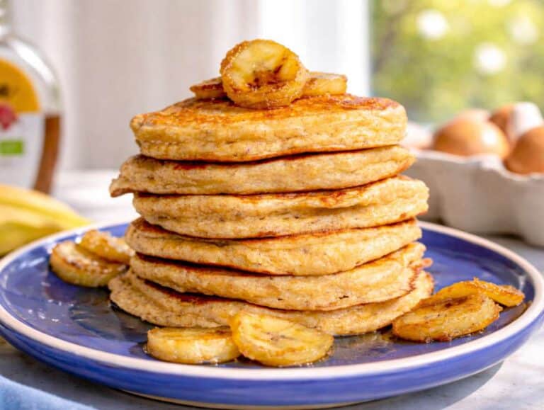 Step 5 Freshly cooked banana oatmeal pancakes stacked on a plate with warm sautéed bananas.