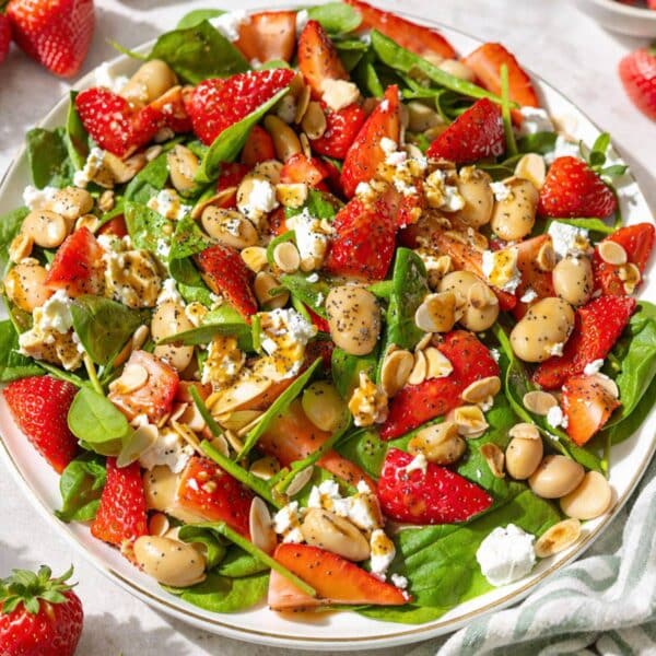 Strawberry spinach salad on marble table near window with bright Mediterranean light.