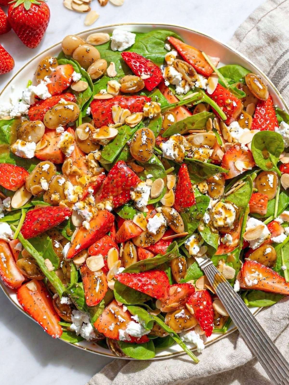 Strawberry spinach salad with feta almonds and beans on platter in bright natural light.