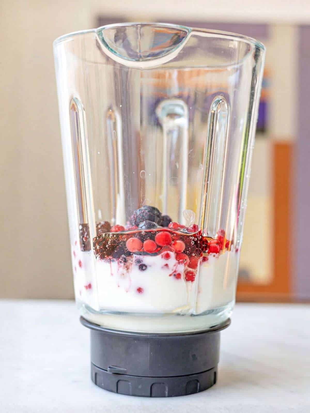 Blender filled with ingredients for the berry smoothie.