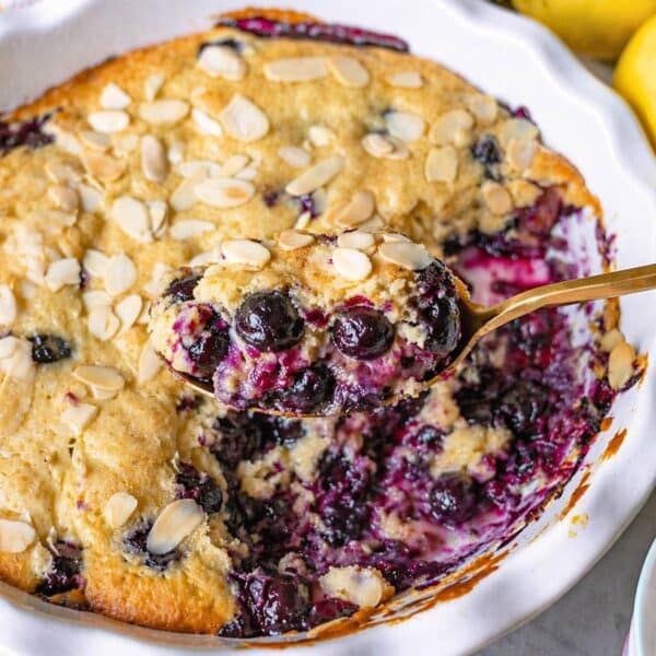 Blueberry spoon cake scooped from the dish with a golden spoon.